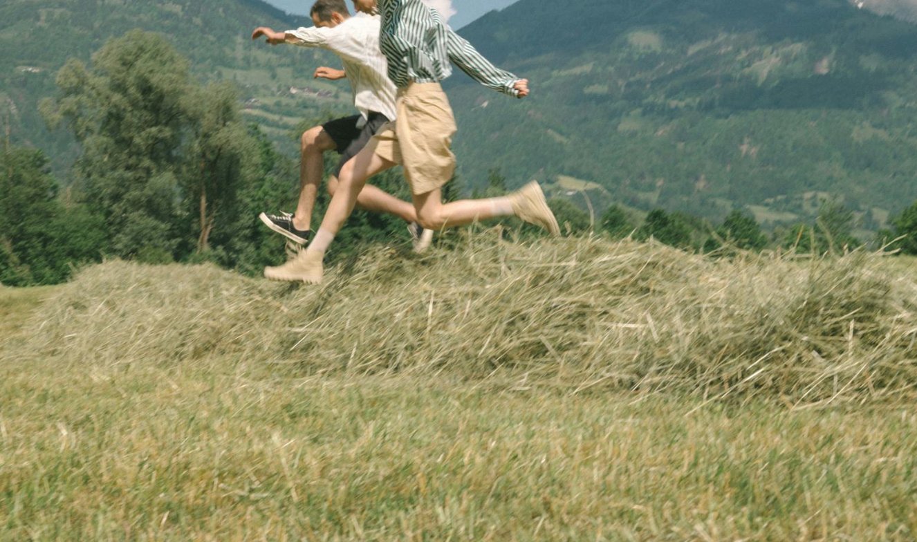 Two people leaping across a sunlit field
